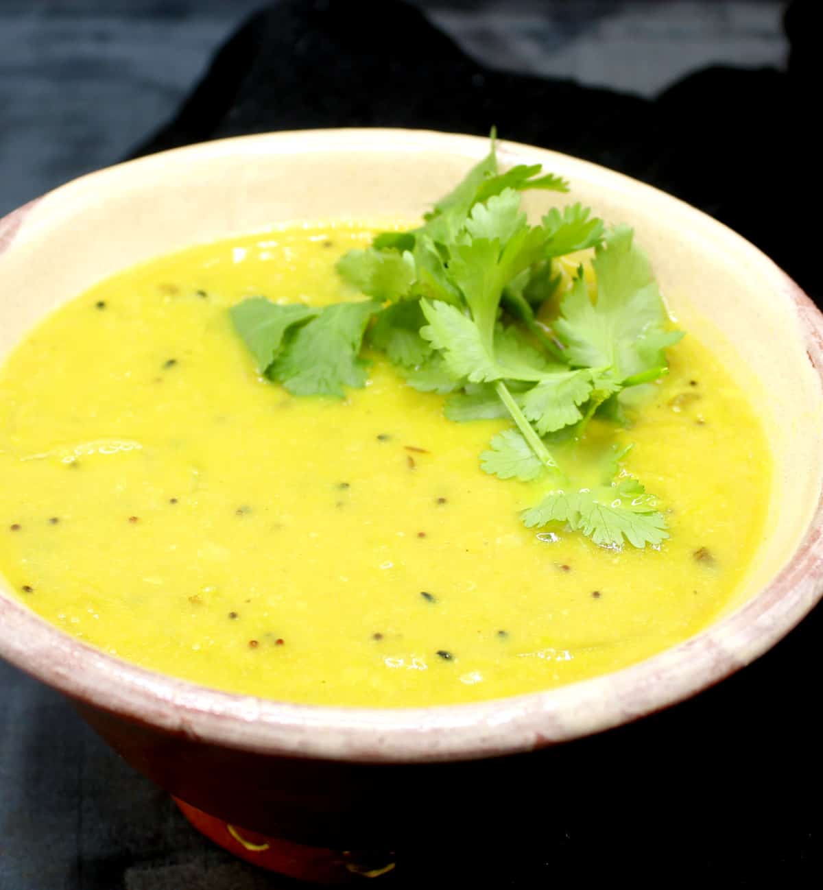 Bengali dal with panch phoron in bowl with cilantro garnish.