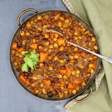 Chickpea tagine in copper serving pan with spoon.
