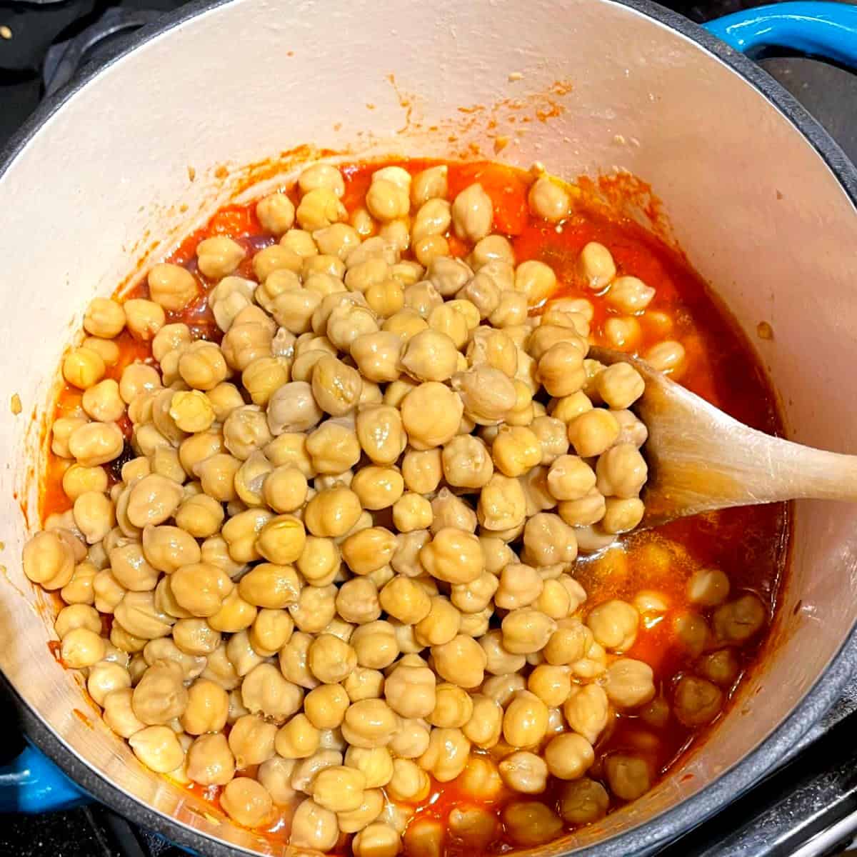 Chickpeas added to tomatoes in Dutch oven.