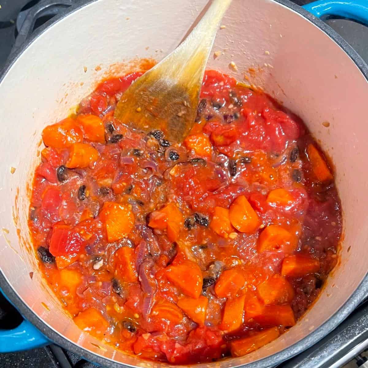 Tomater läggs till tagine i holländsk ugn.