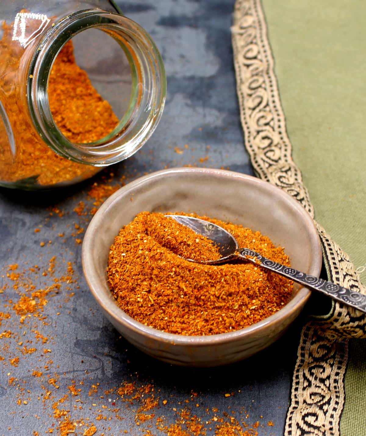 Marockansk ras el hanout kryddblandning i skål med sked och i glasbehållare.