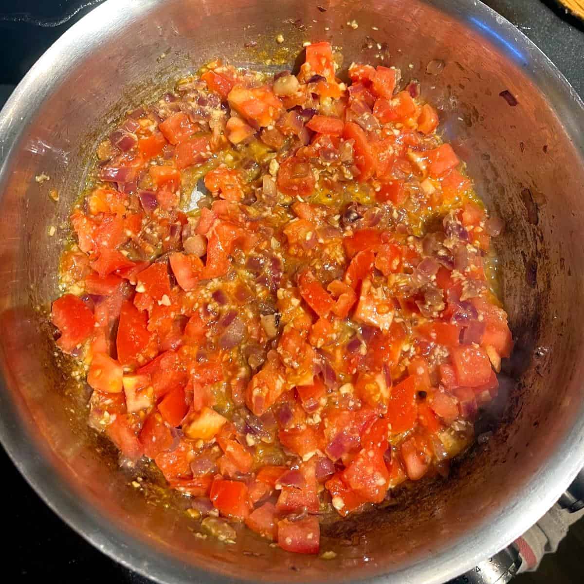 Tomatoes and onions in saucepan.