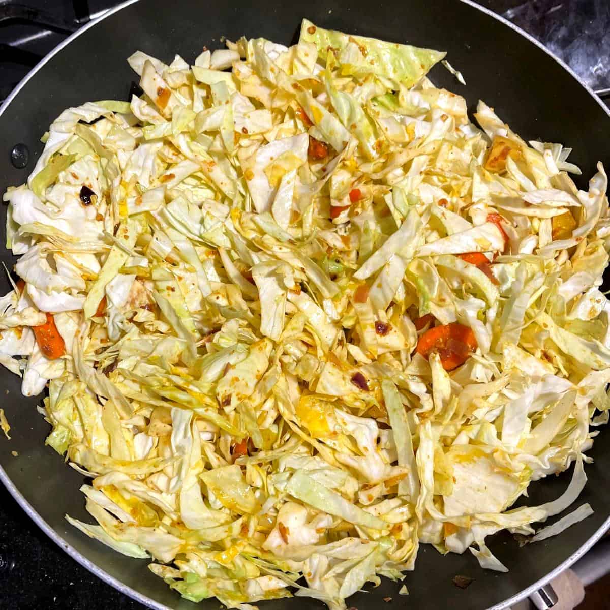 Cabbage mixed with spices in wok.