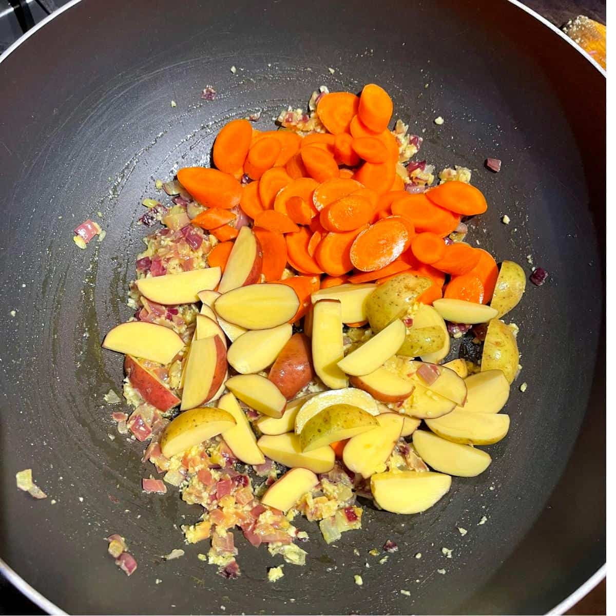 Morötter och potatis läggs till tikil gomen wok.