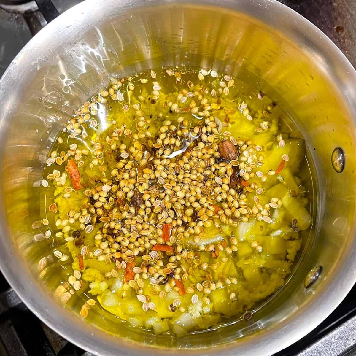 Spices, herbs in saucepan with olive oil.