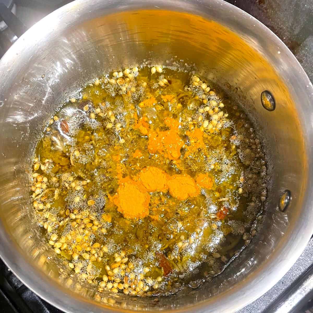 Turmeric added to nitter kibbeh in saucepan.