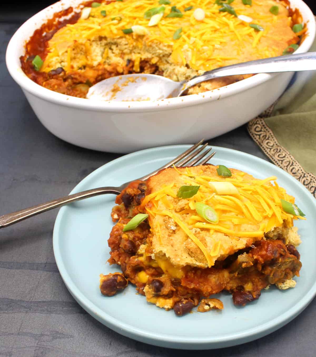 A portion of vegan tamale pie in blue plate with casserole in background.