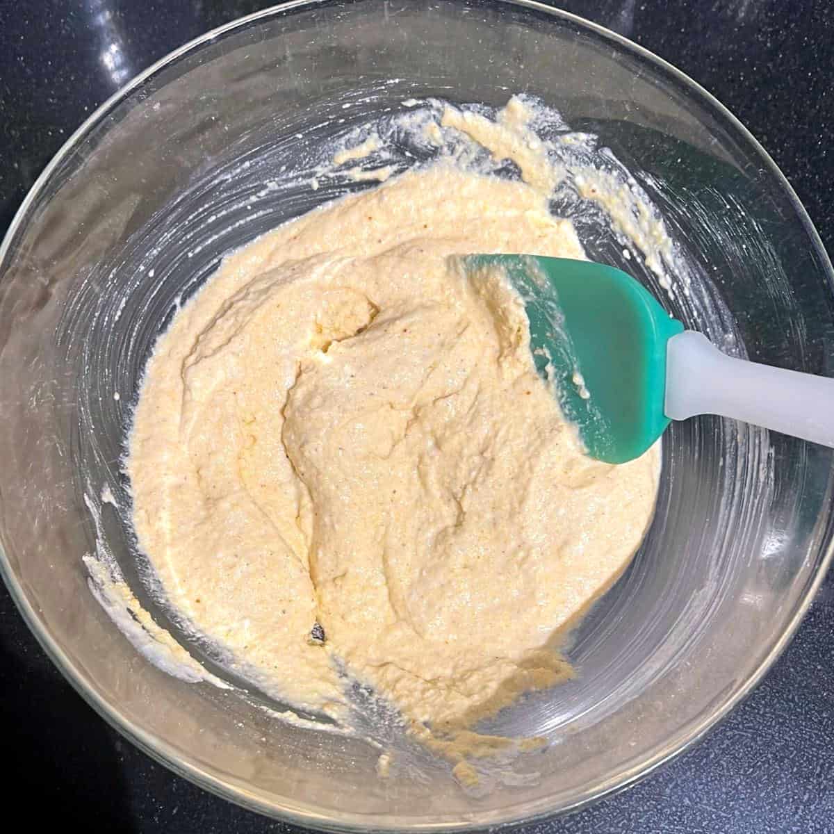 Cornbread mixture in bowl with spatula.