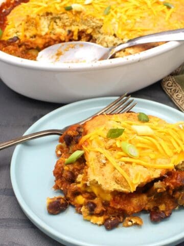 Vegan tamale pie slice in blue plate and casserole in background.