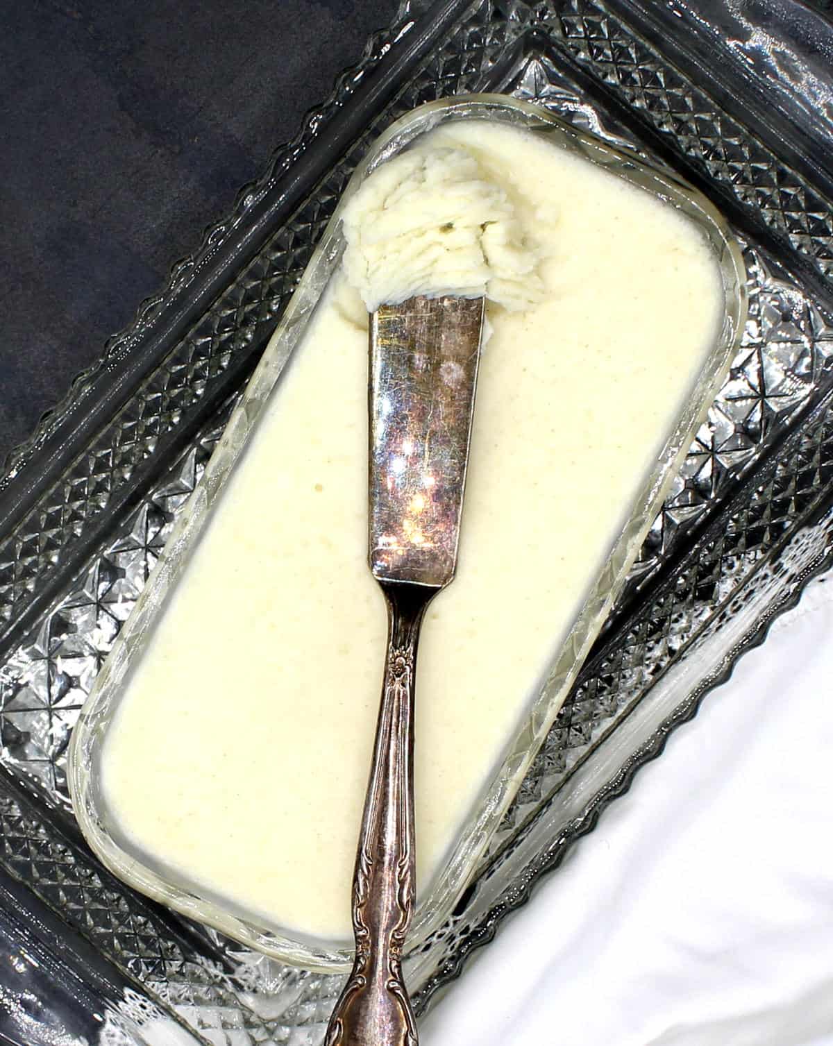 Spreadable vegan butter in crystal butter dish with butter knife.
