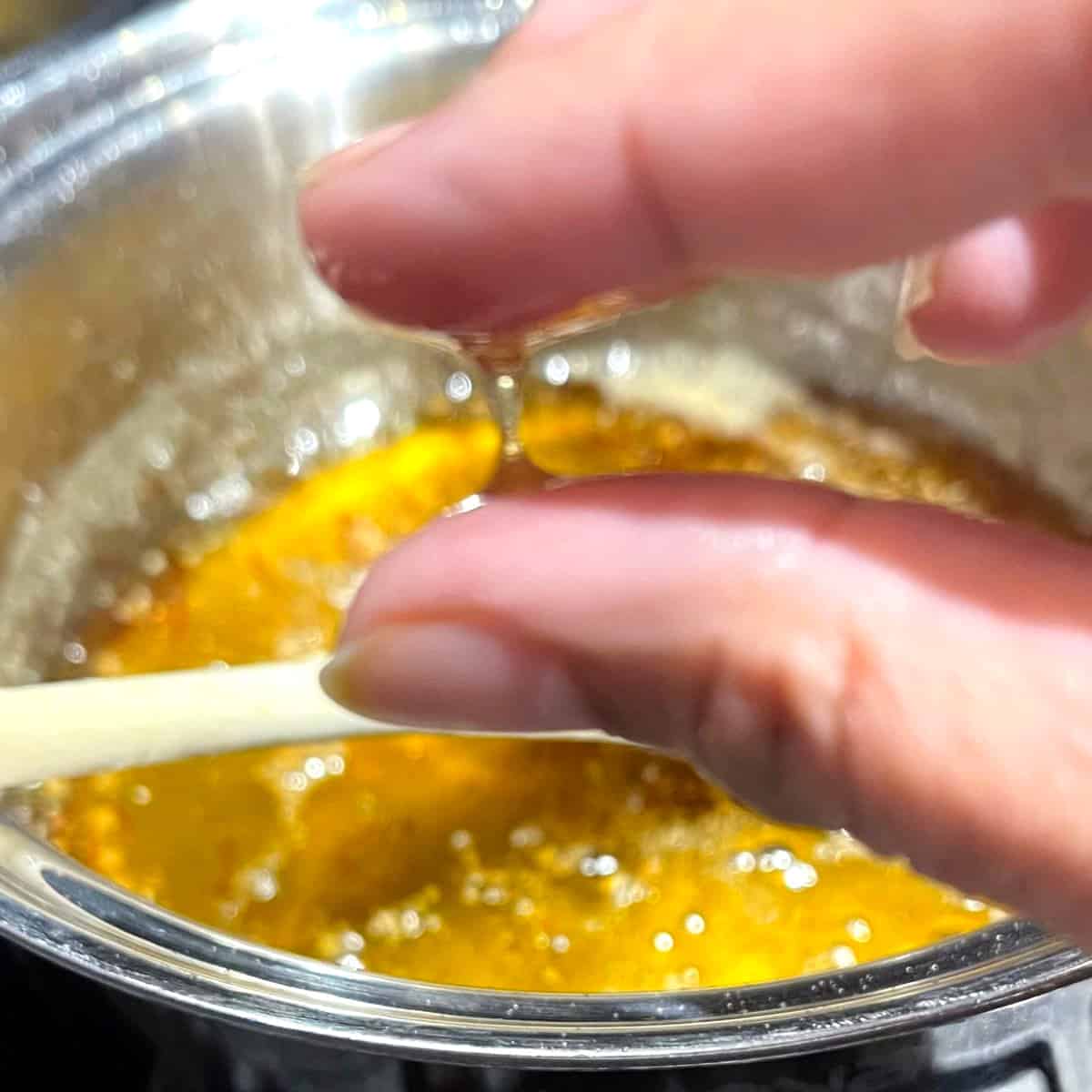 Two fingers showing one-string consistency of sugar syrup.