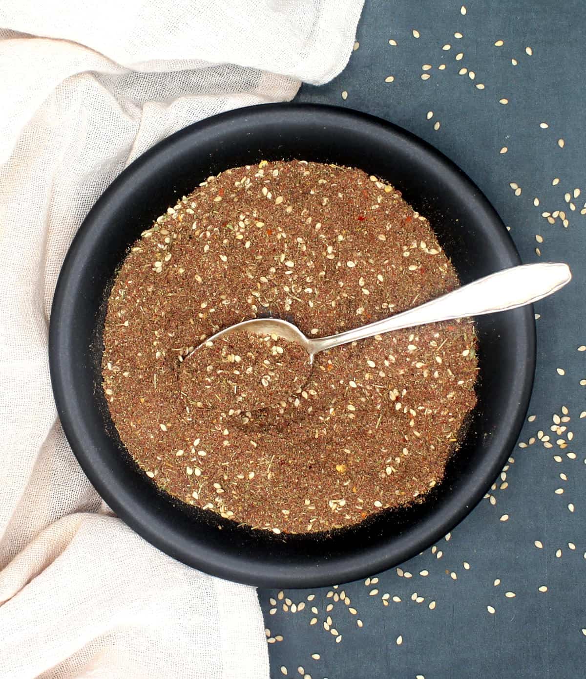 Za'atar spice blend in black plate with spoon.