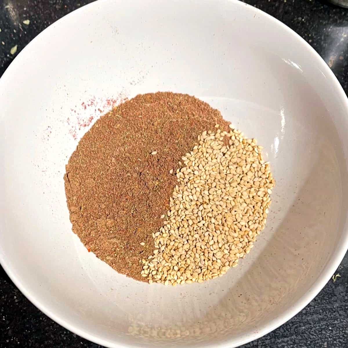 Blended herbs mixed with sesame seeds in bowl.