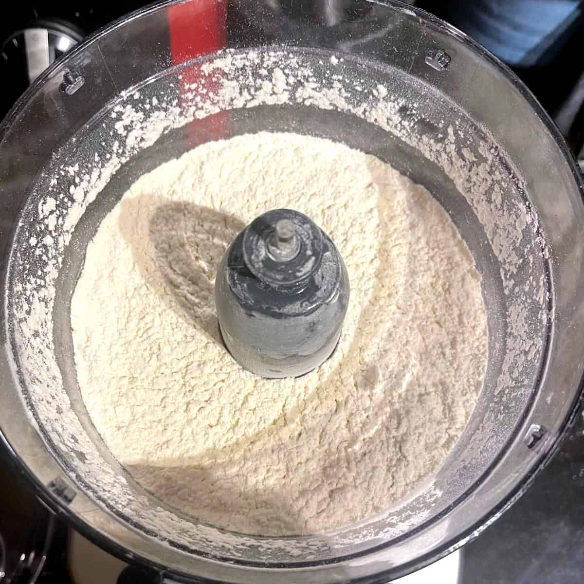 Dry ingredients for vegan empanada dough mixed in food processor.