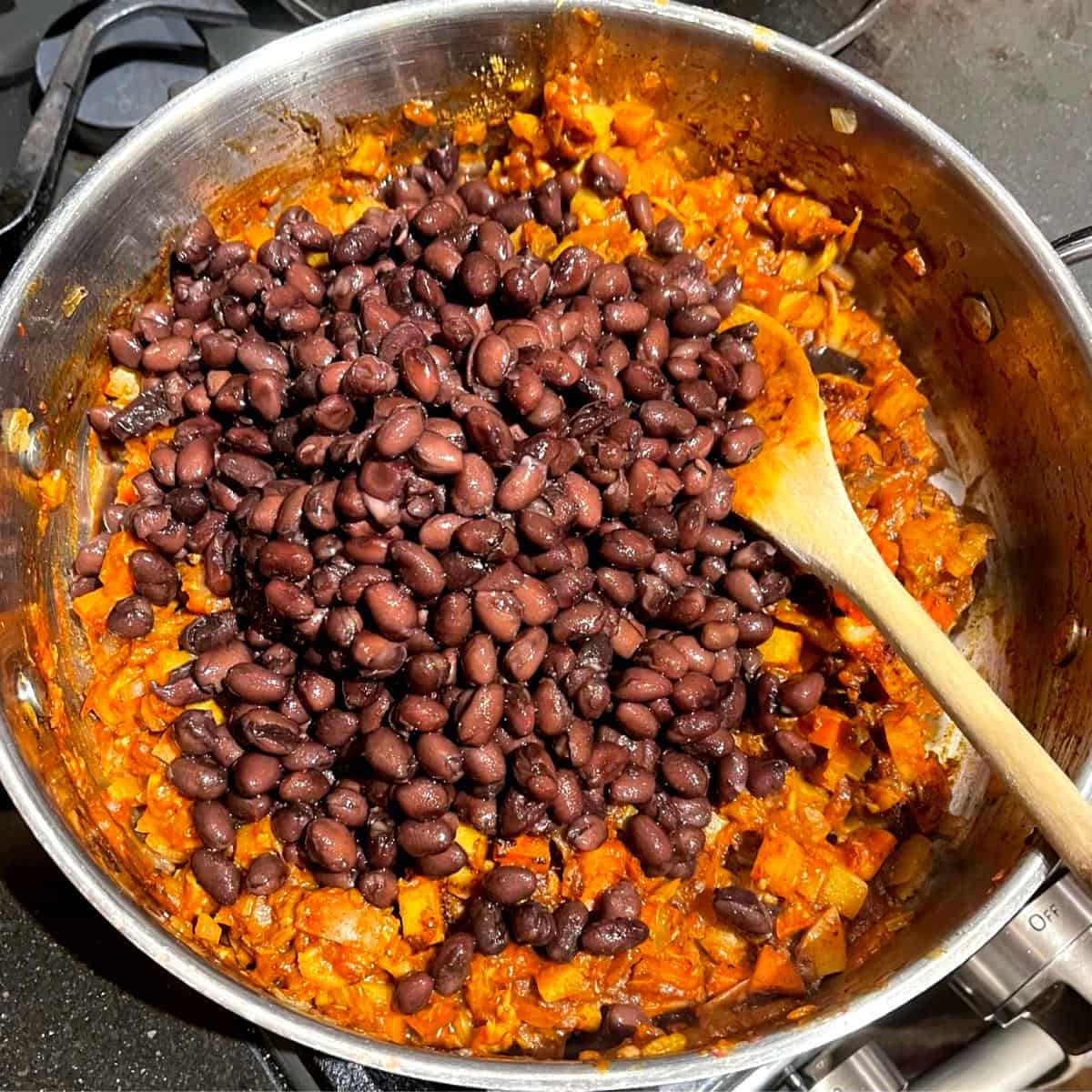 Black beans added to veggies in skillet.