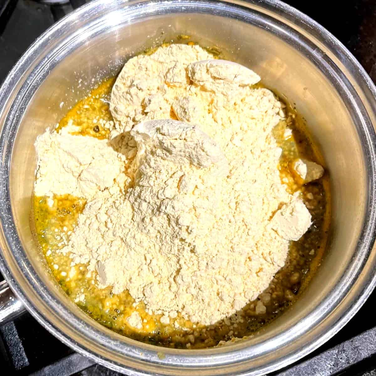 Besan or chickpea flour added to saucepan with water and seasonings.