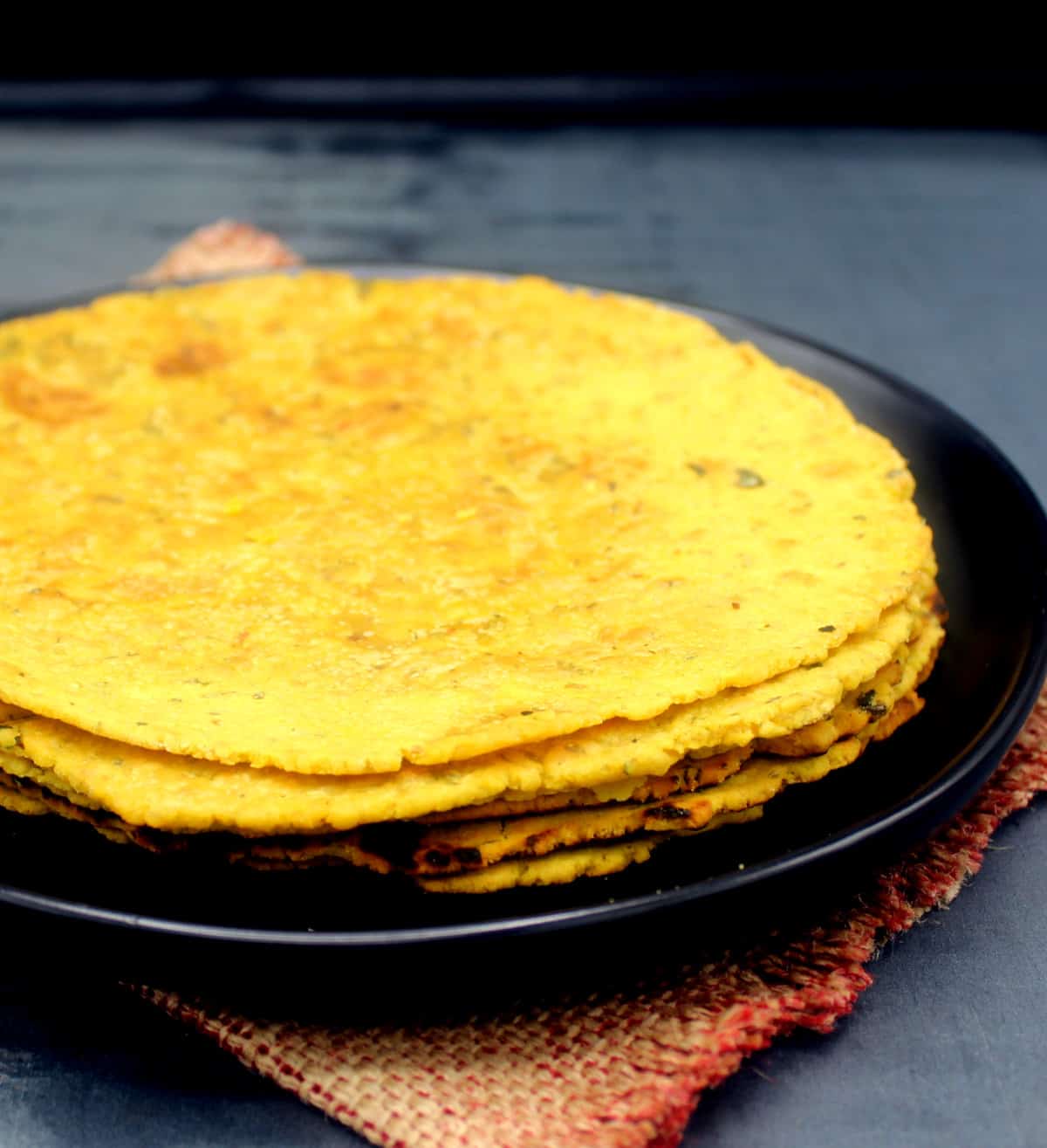 Stack of besan roti on a black plate.