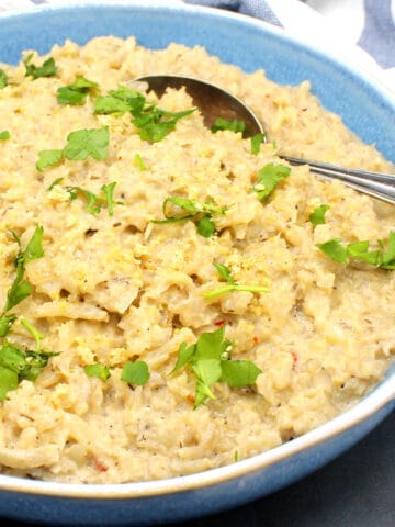 Creamy cauliflower risotto in blue bowl with spoon.