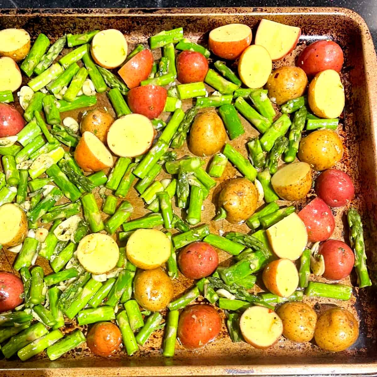 Asparagus and potatoes on baking sheet before baking.