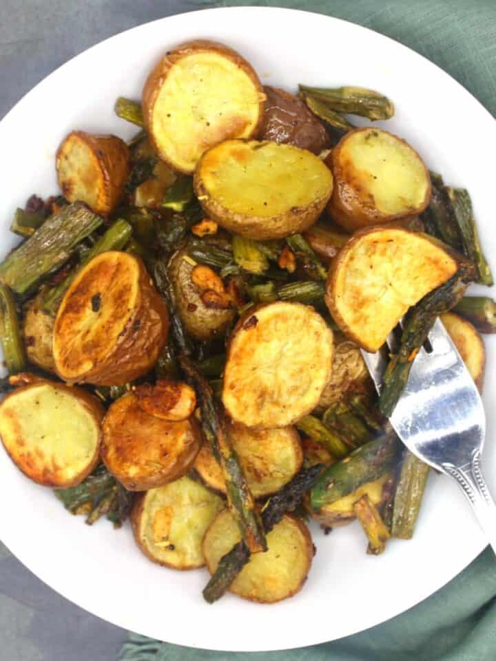 Roasted asparagus and potatoes in white bowl.