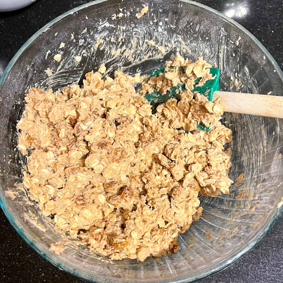 Oatmeal cookie batter in glass bowl with spatula.