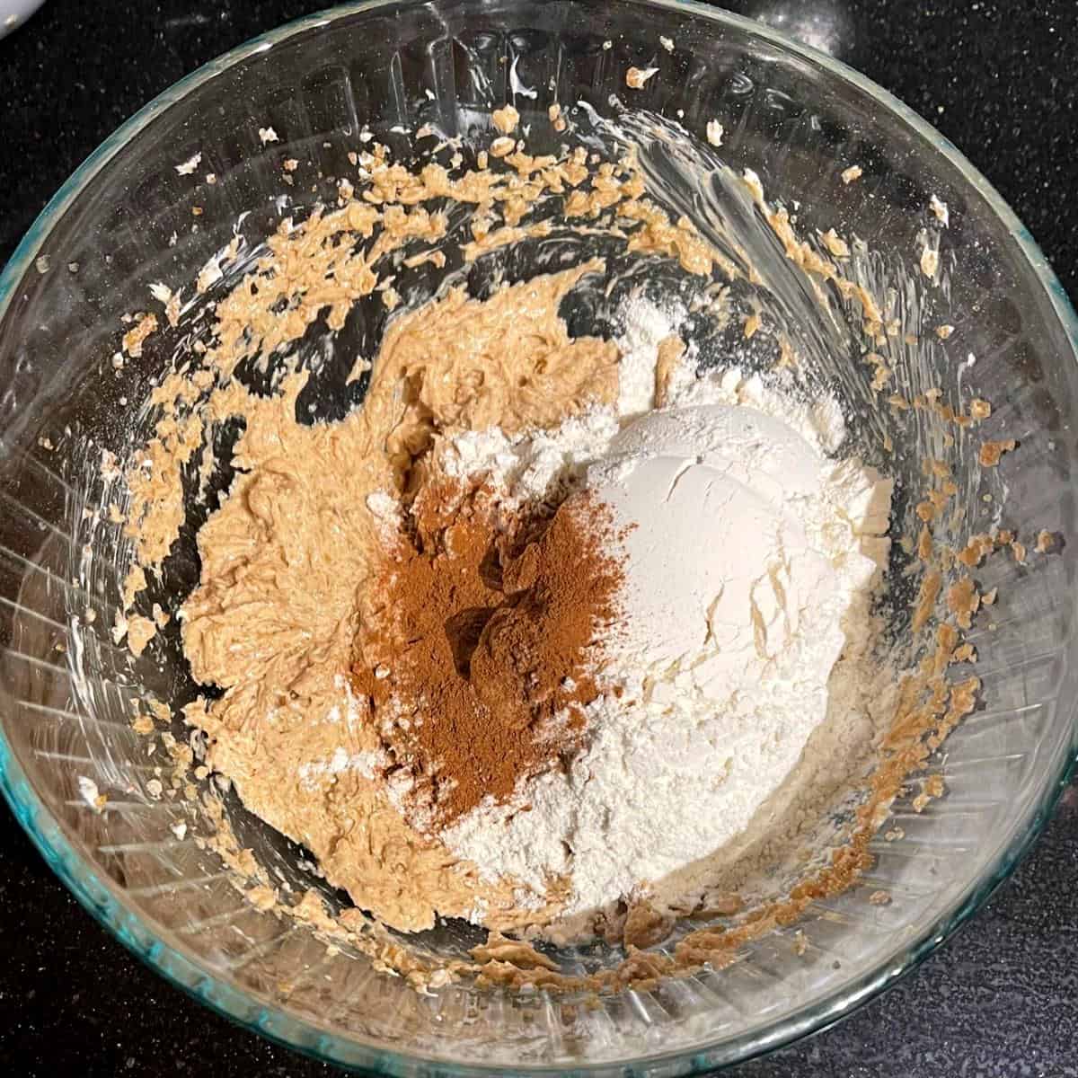 Ground cinnamon and flour added to cookie batter for oatmeal cookies.