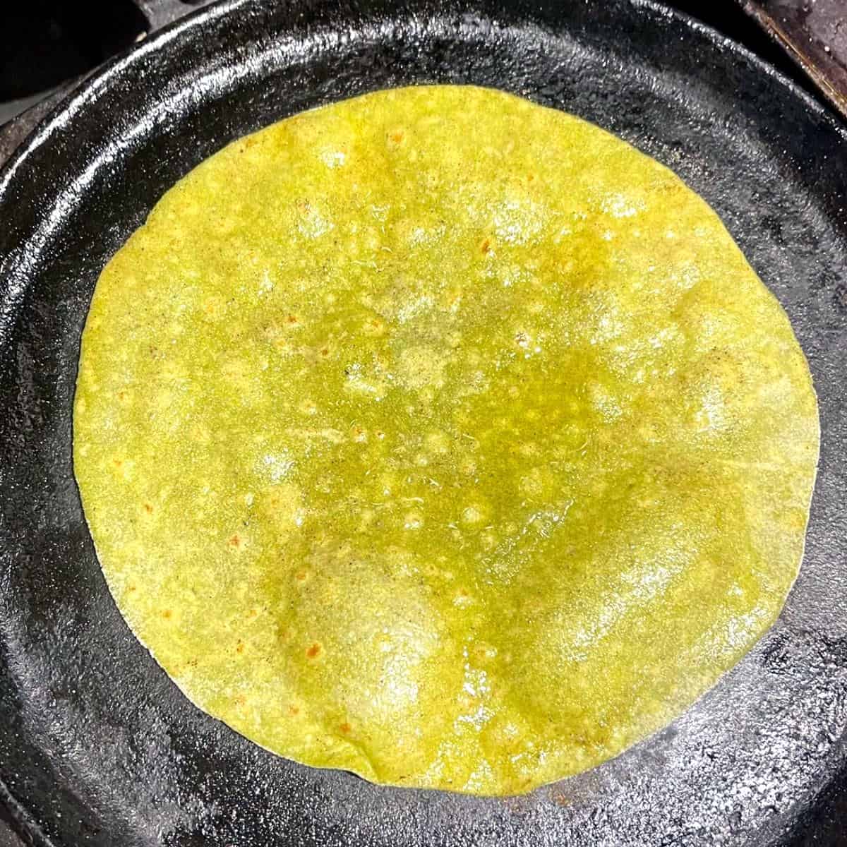 High protein spinach and sprouts roti roasting on cast iron griddle.