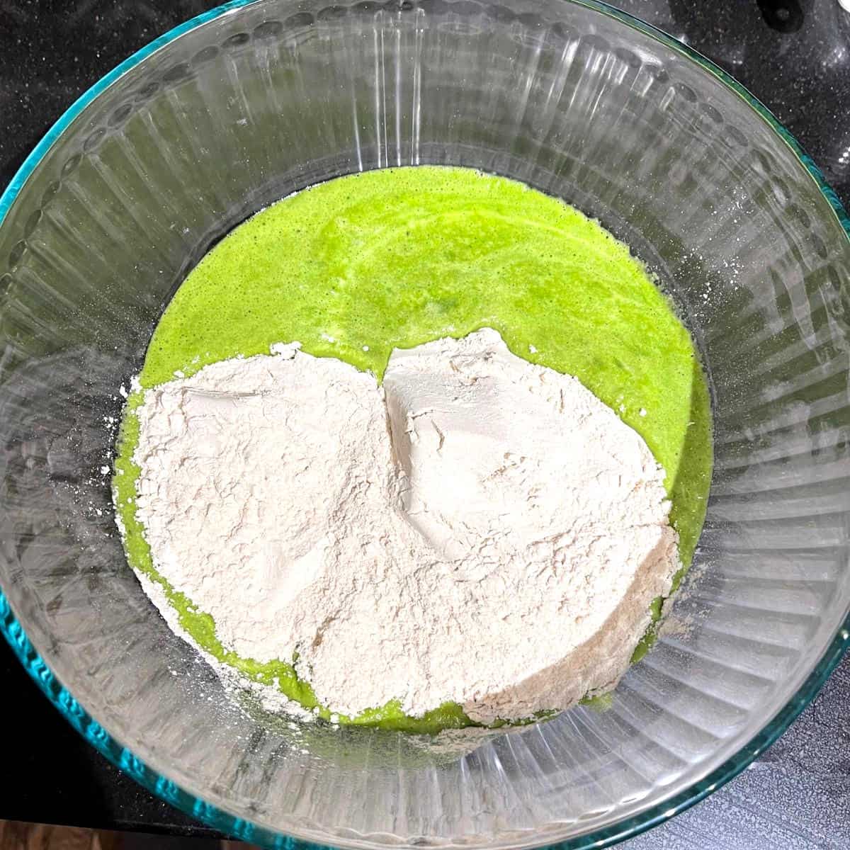 Spinach and mung bean blended paste with whole wheat atta flour in bowl.