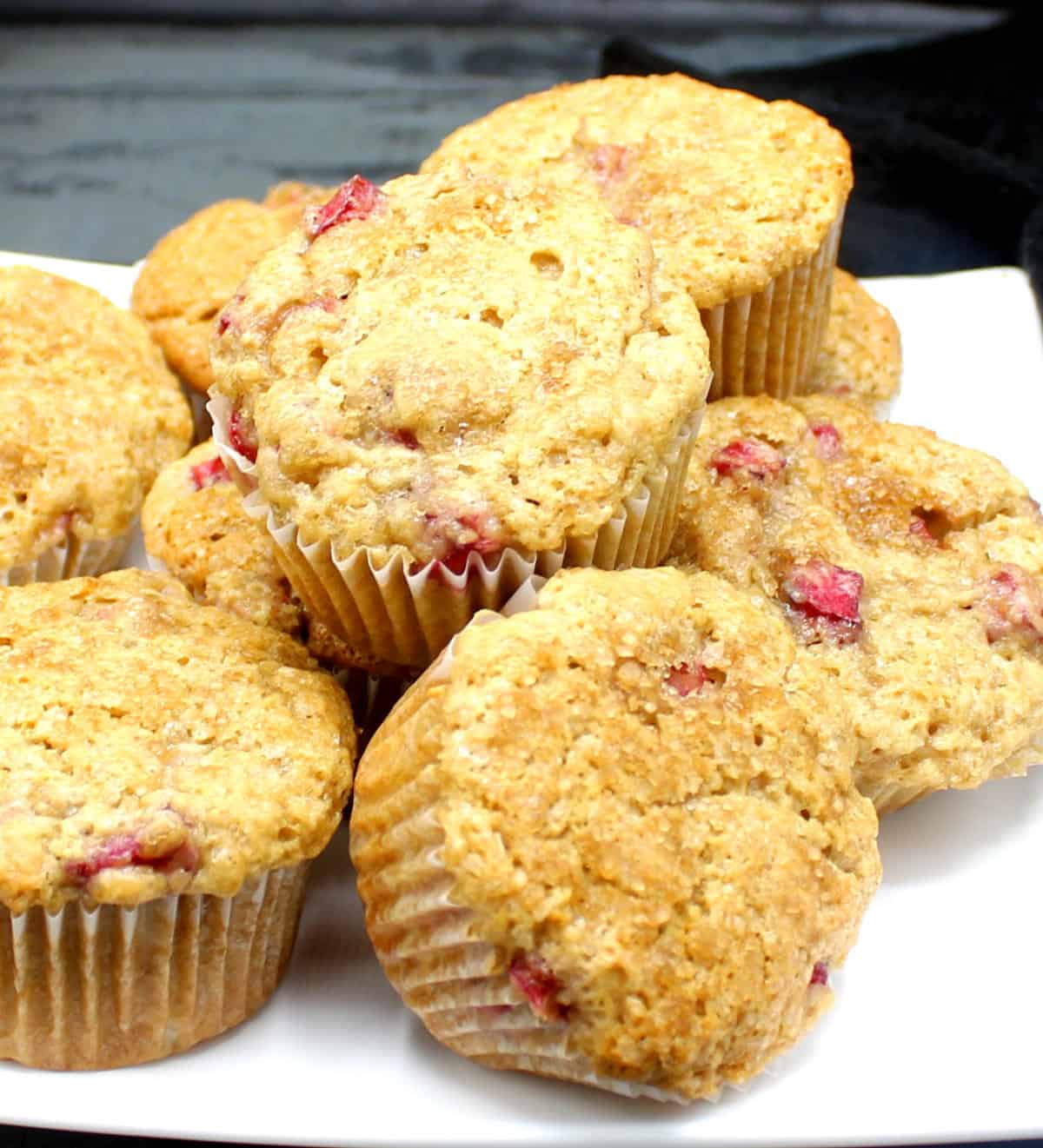 Vegan rhubarb muffins stacked on white plate.