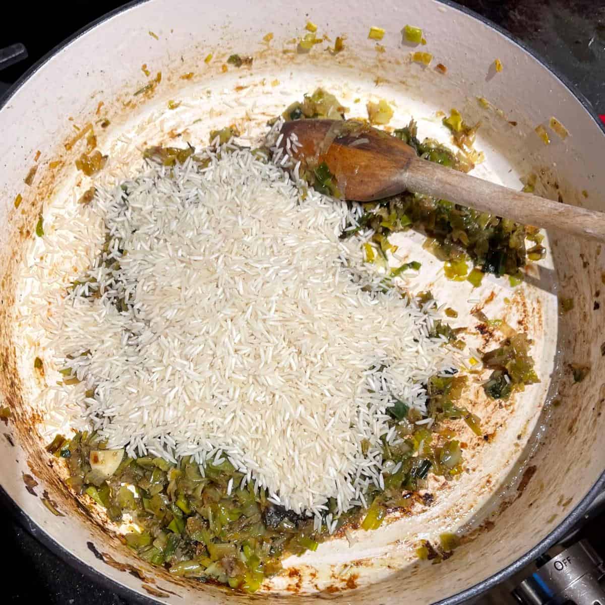 Rice added to leeks in saucepan.