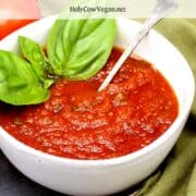 Tomato sauce in bowl with spoon and basil and text that says 