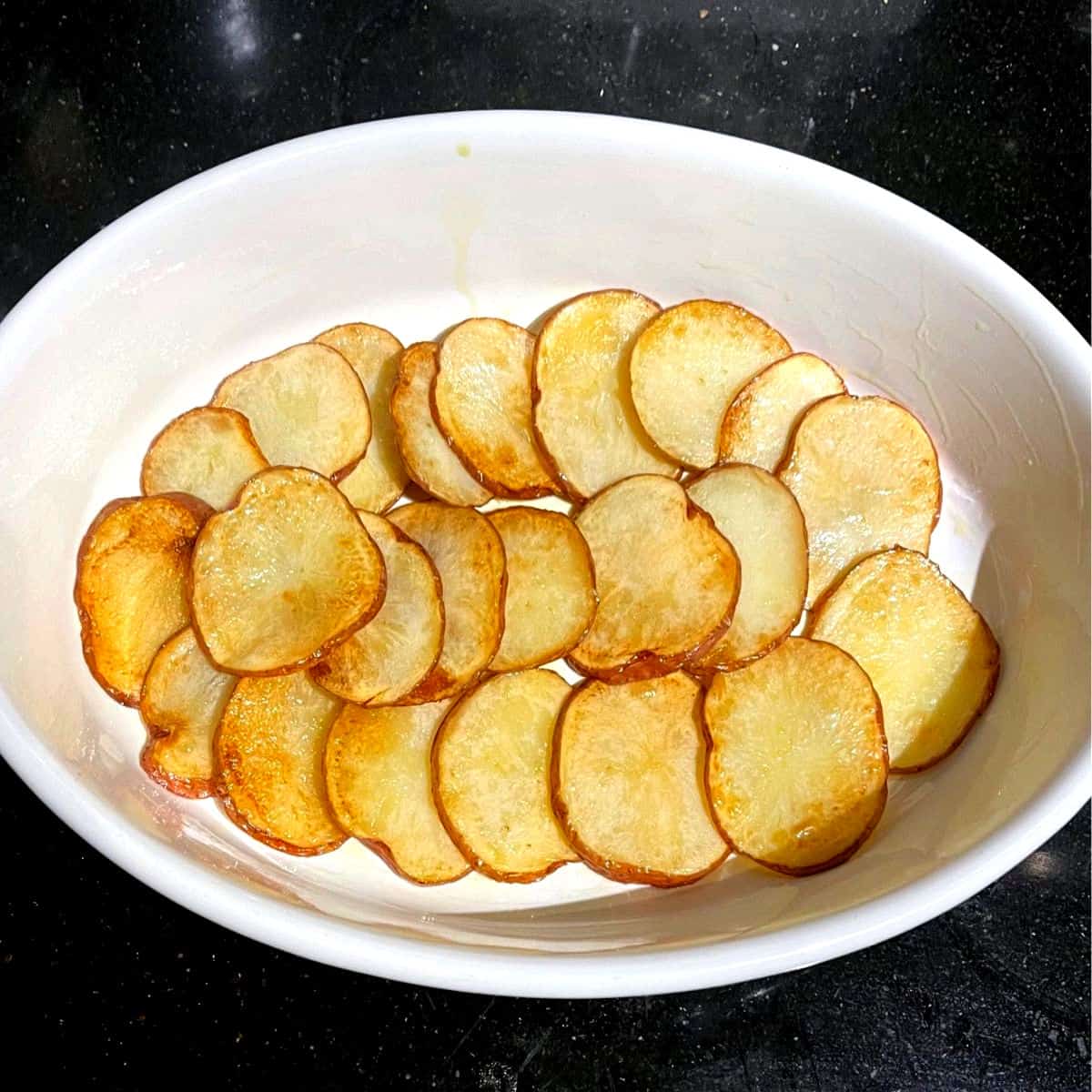 Potato layered in baking dish for vegan moussaka.