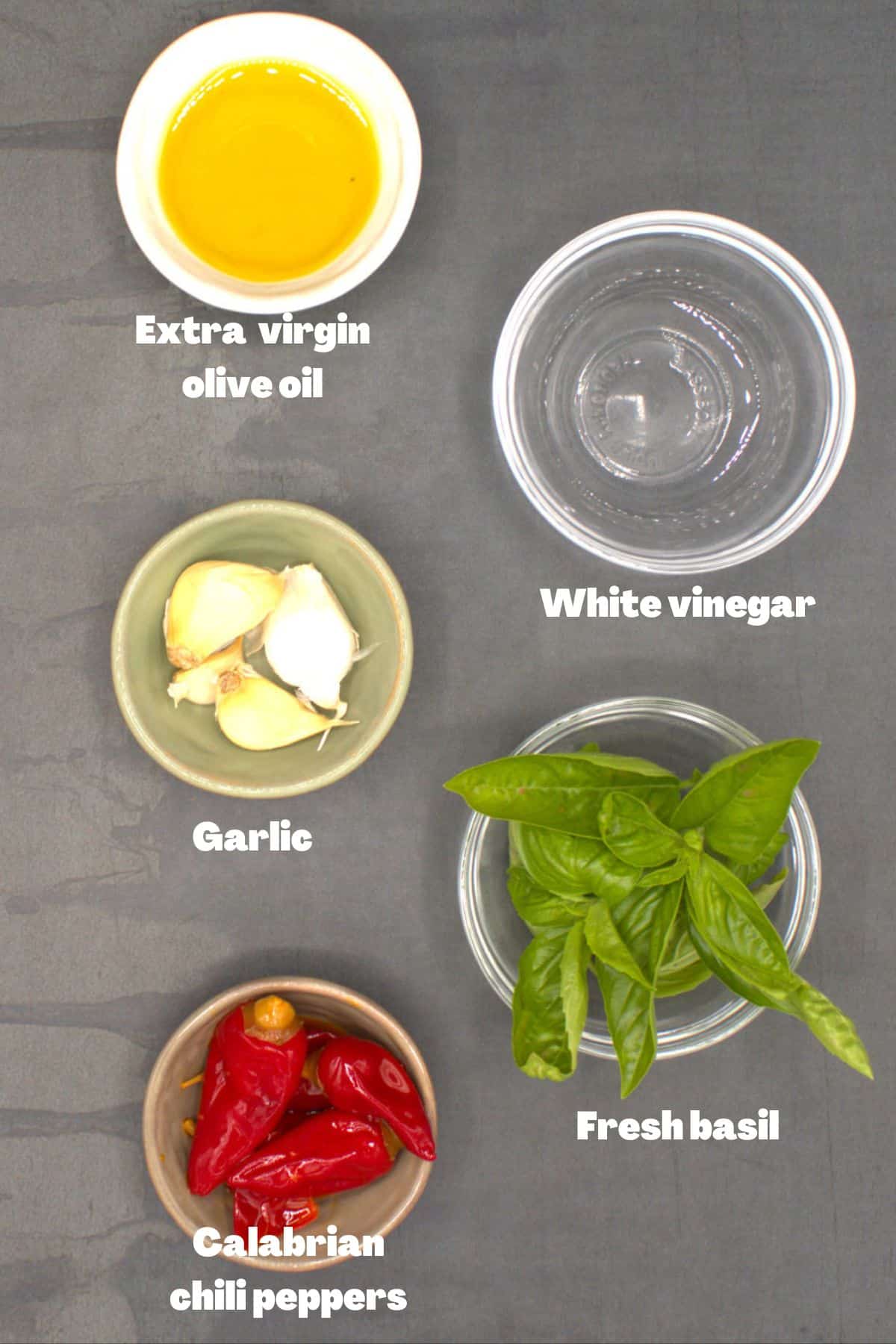 Ingredients for Calabrian chili paste, including garlic, olive oil, basil, vinegar and Calabrian chili peppers.