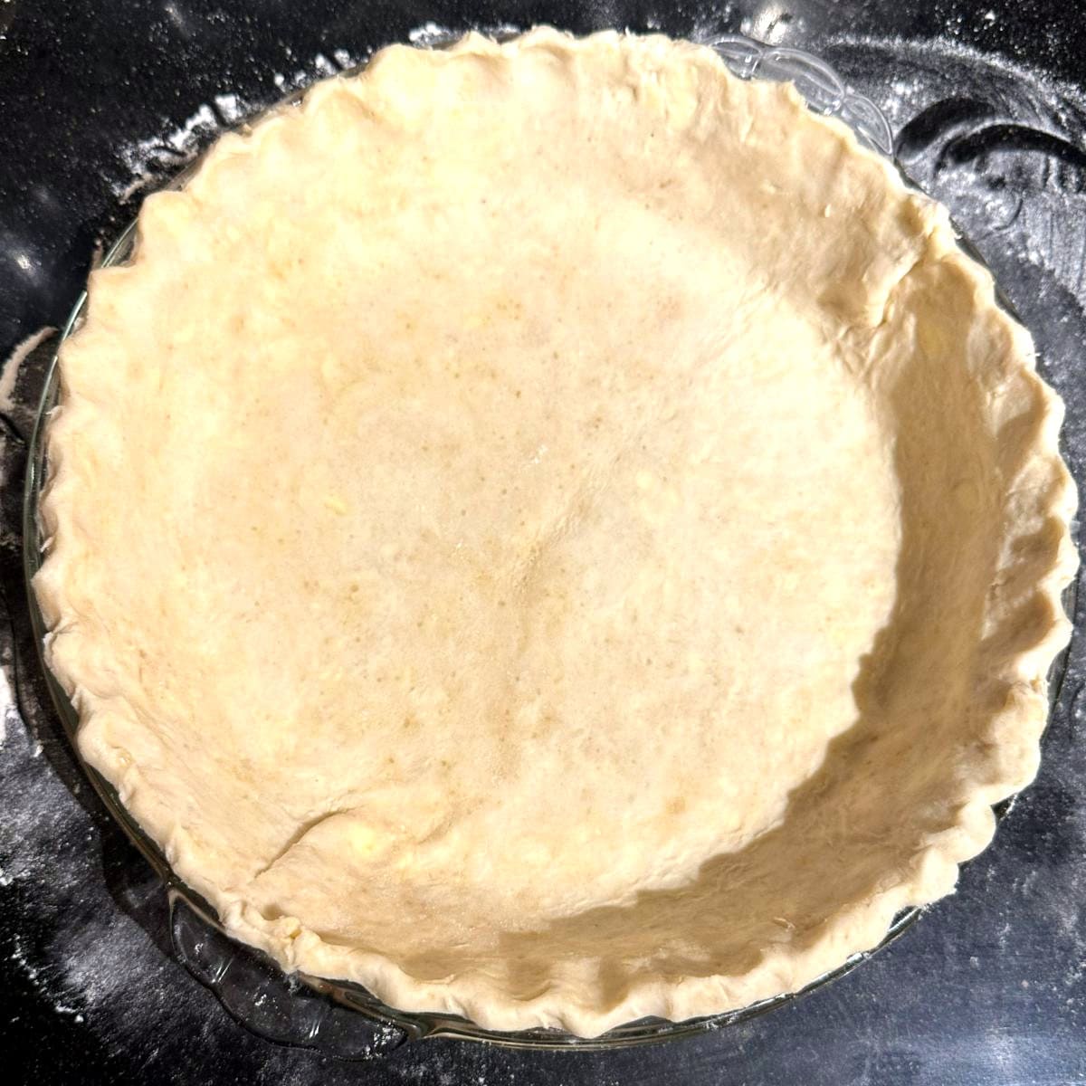 Bottom crust of vegan apple pie in pie plate.