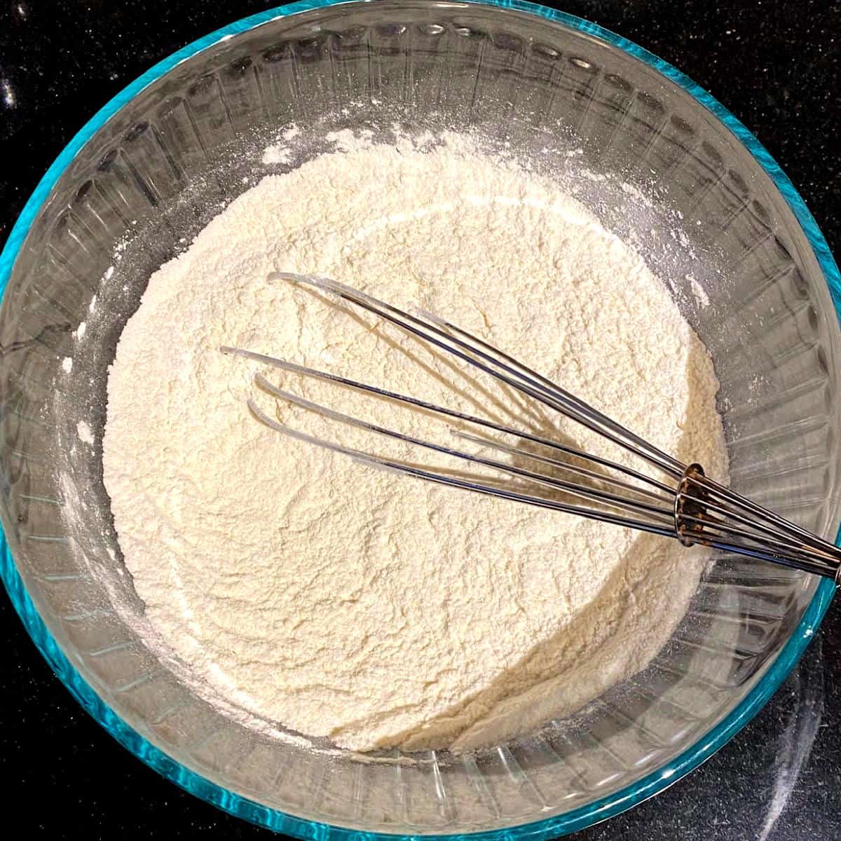Dry ingredients for vegan pound cake in bowl with whisk.
