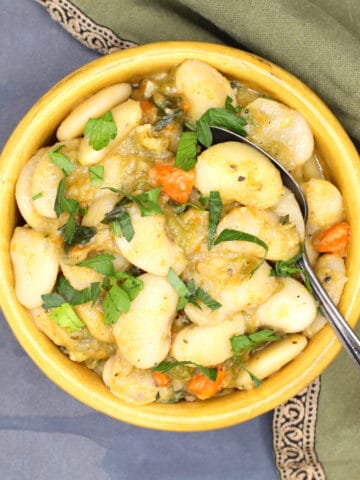Creamy butter beans in yellow bowl with spoon.