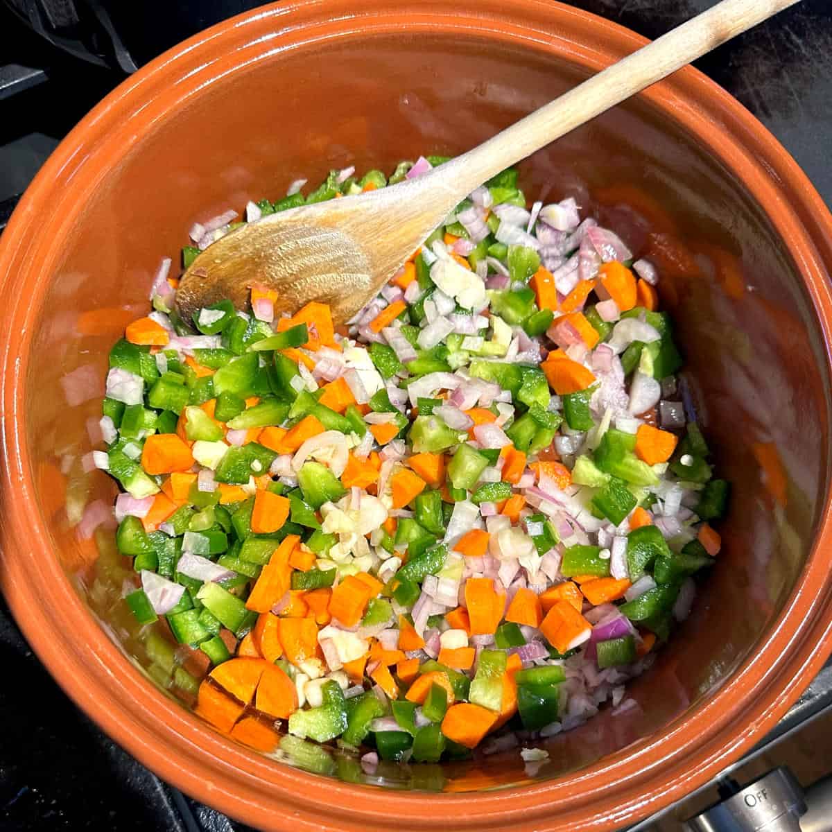Carrots, onions and bell peppers in pot with onions.