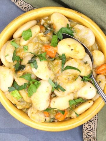 Creamy butter beans in bowl with parsley garnish and spoon.