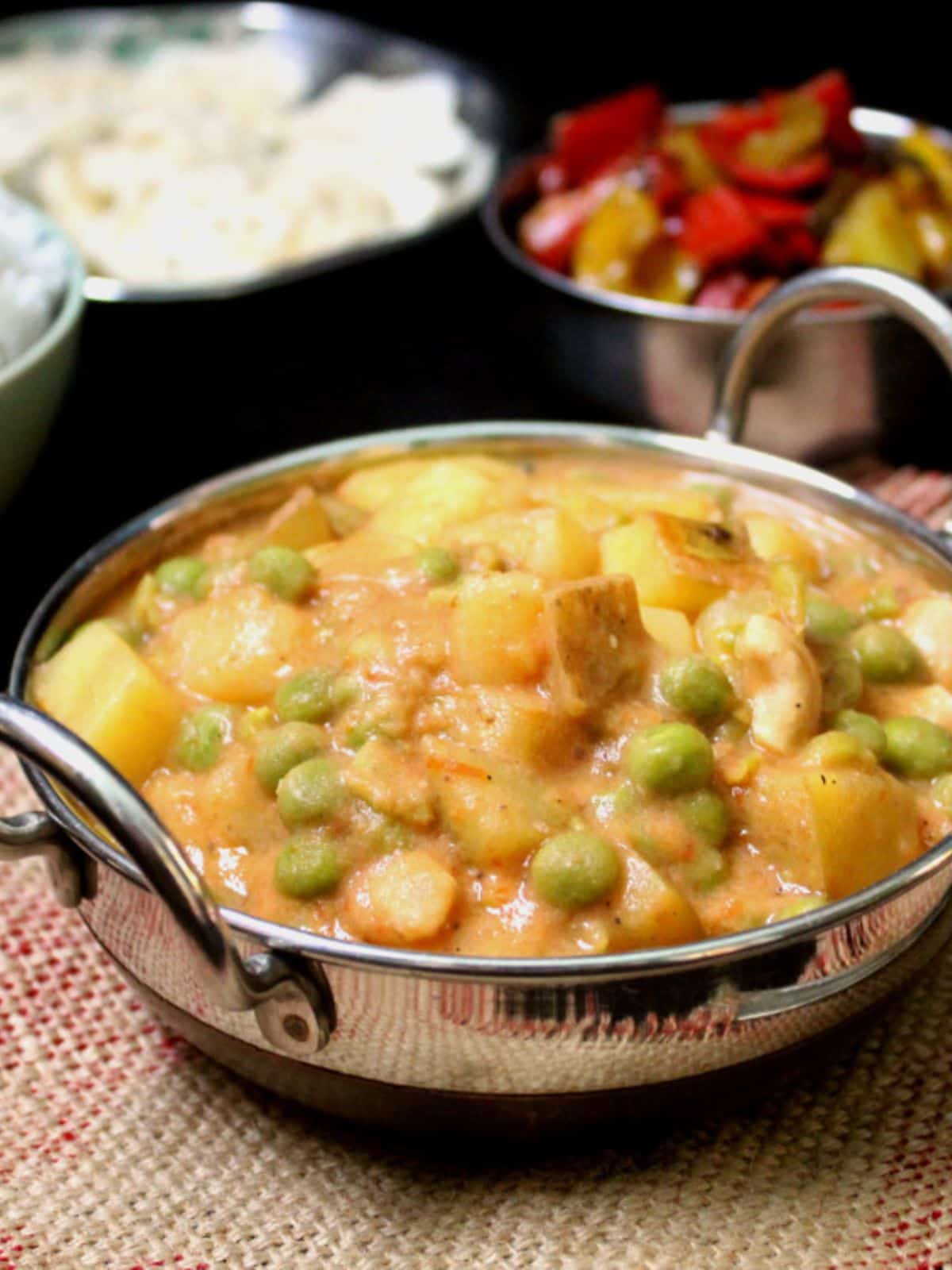 Peas potato curry with rice and a vegetable dish in background.
