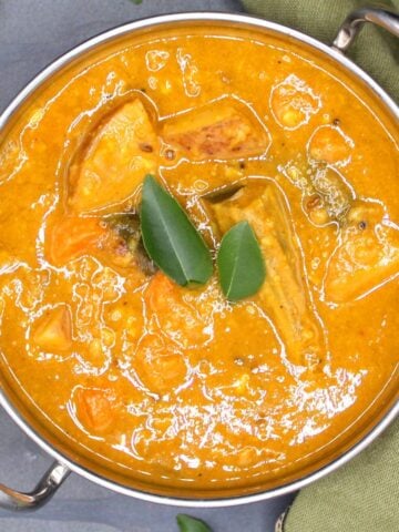 Sambar in karahi bowl with curry leaves.