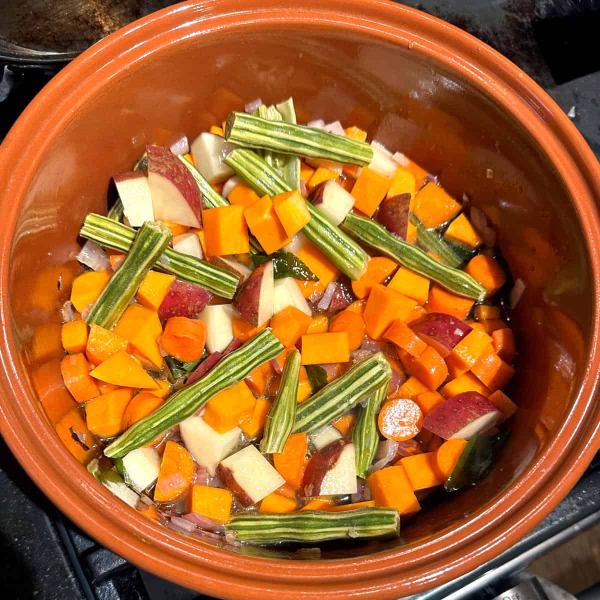 Vegetables--drumsticks, carrots, potatoes and pumpkin -- added to pot for sambar.