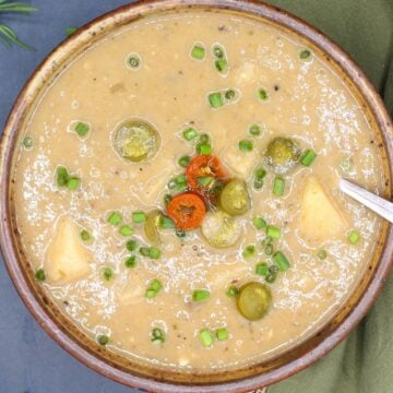 Vegan potato soup in bowl with jalapeno and chives toppings.