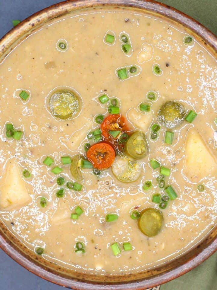 Vegan potato soup in bowl with jalapeno and chives toppings.