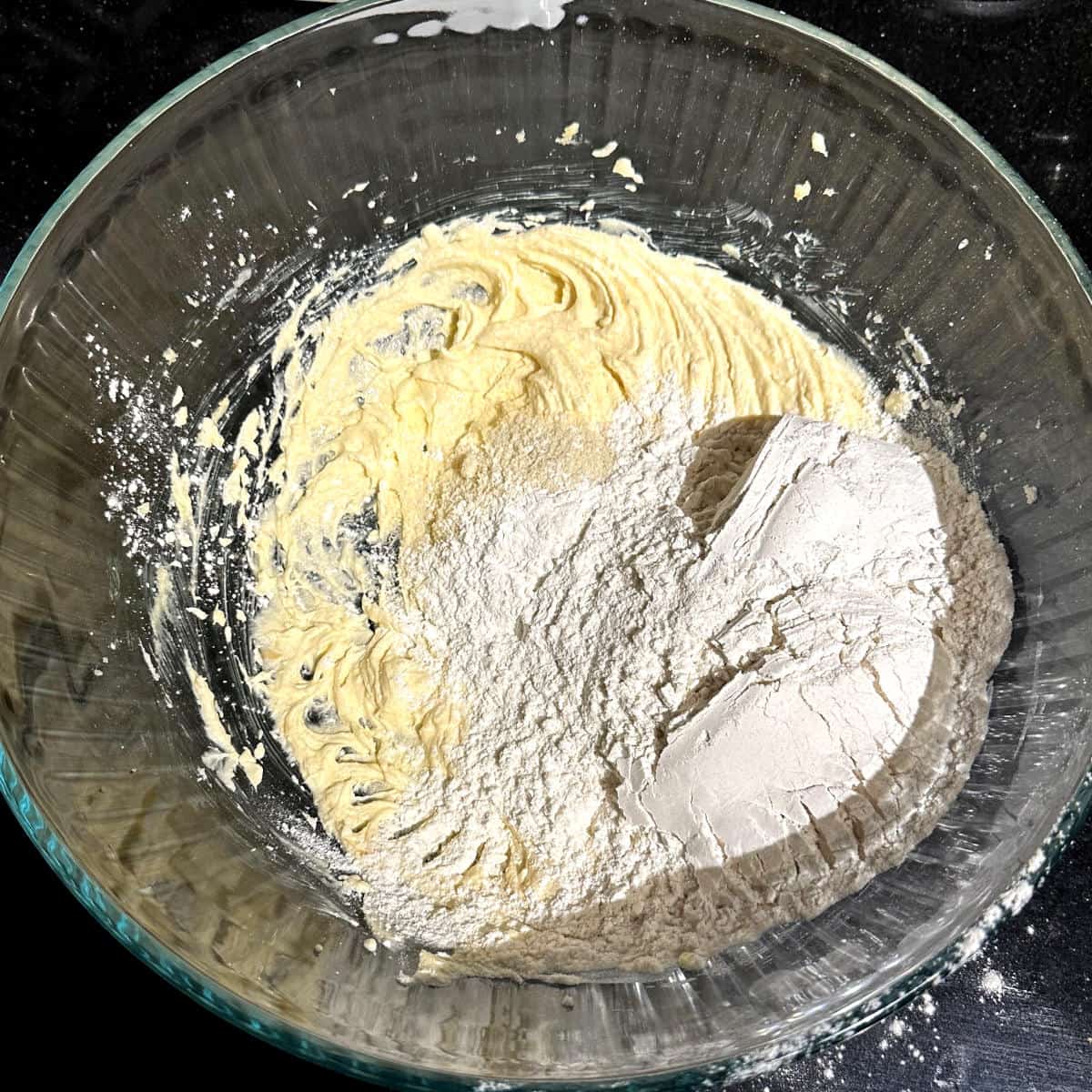 Almond flour and all purpose flour added to glass bowl with butter and sugar.