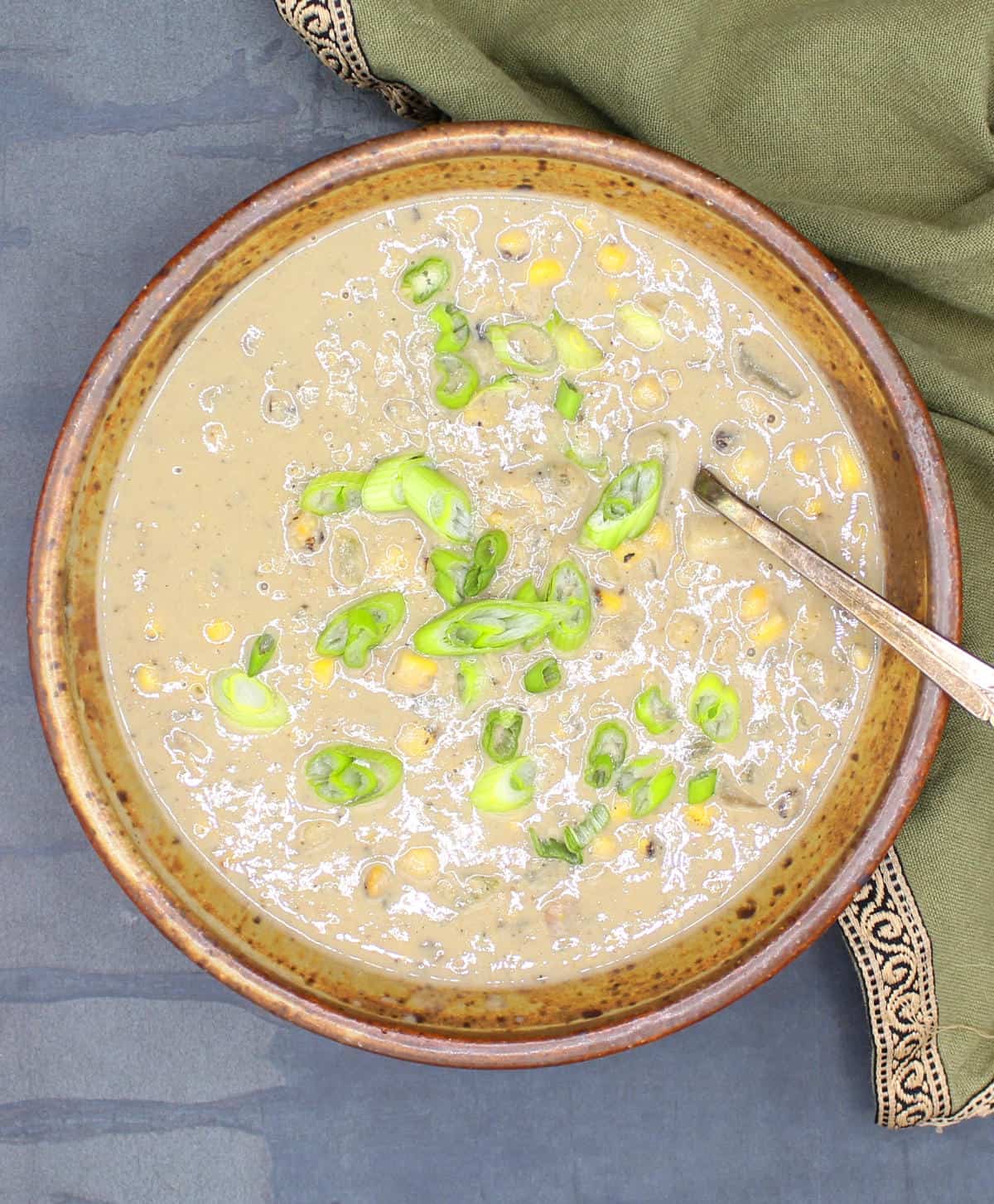 Creamy vegan corn chowder in bowl with scallions.