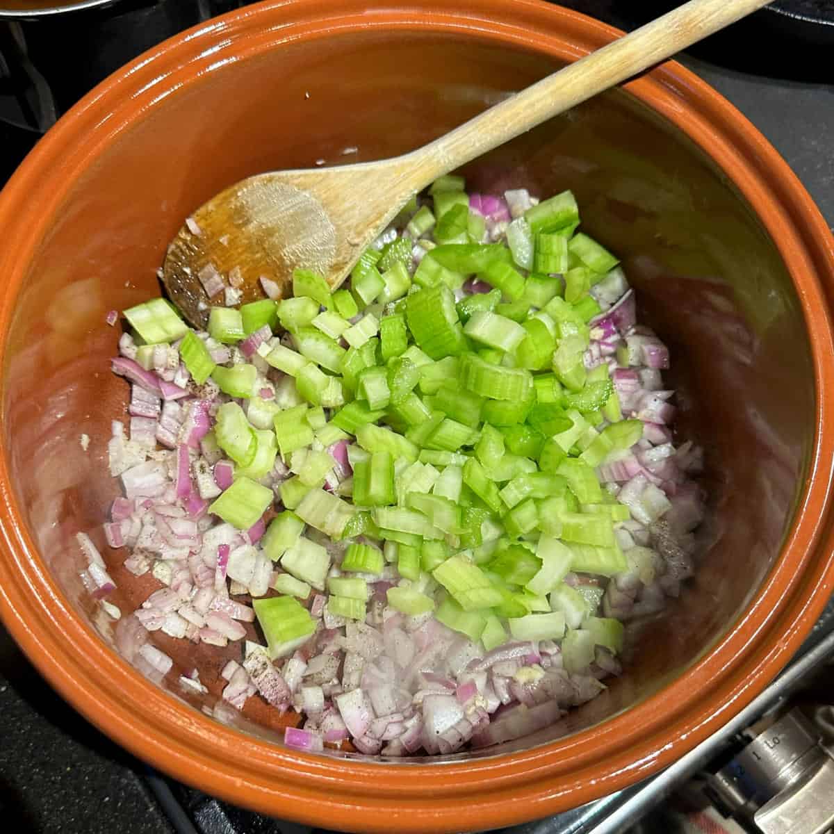 Garlic, celery and onions in pot with ladle.
