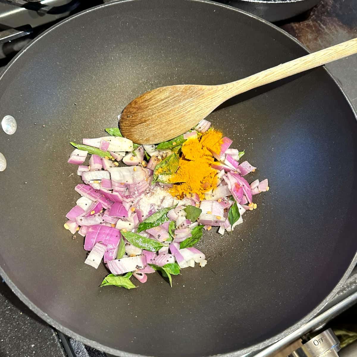 Onions, curry leaves and turmeric added to wok.