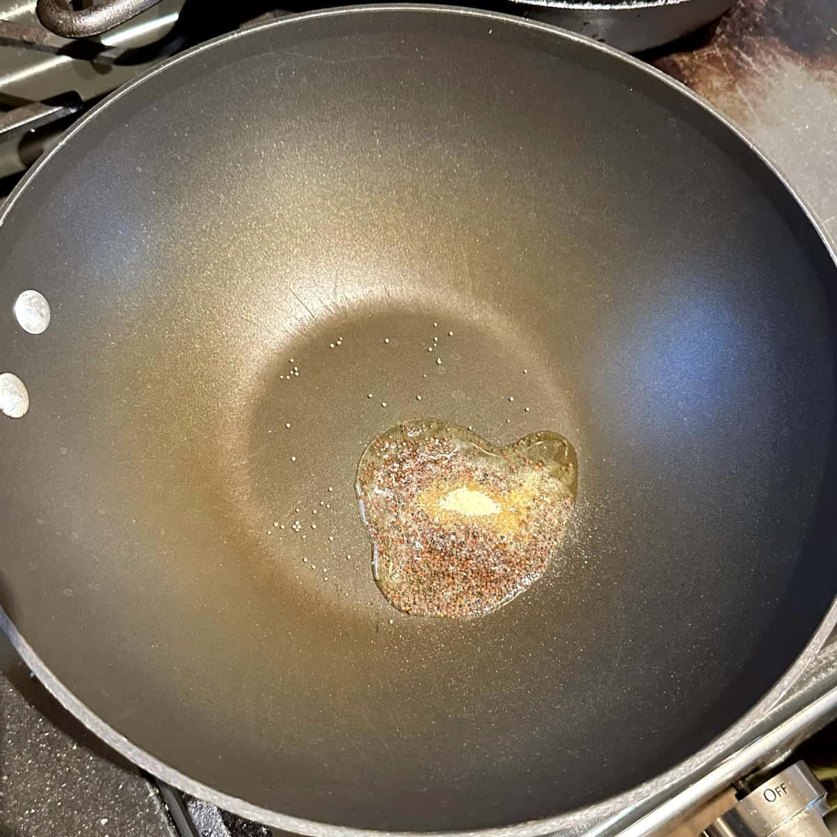 Oil in wok with mustard seeds and asafetida added.