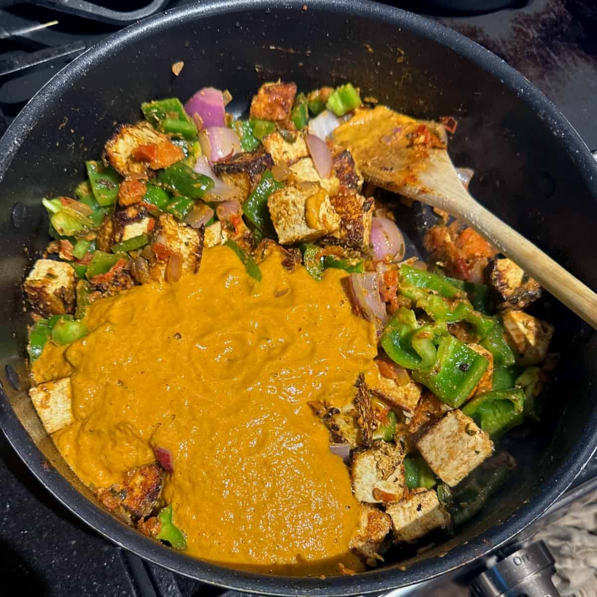 Blended masala and tofu cubes and bell peppers added to saute pan.
