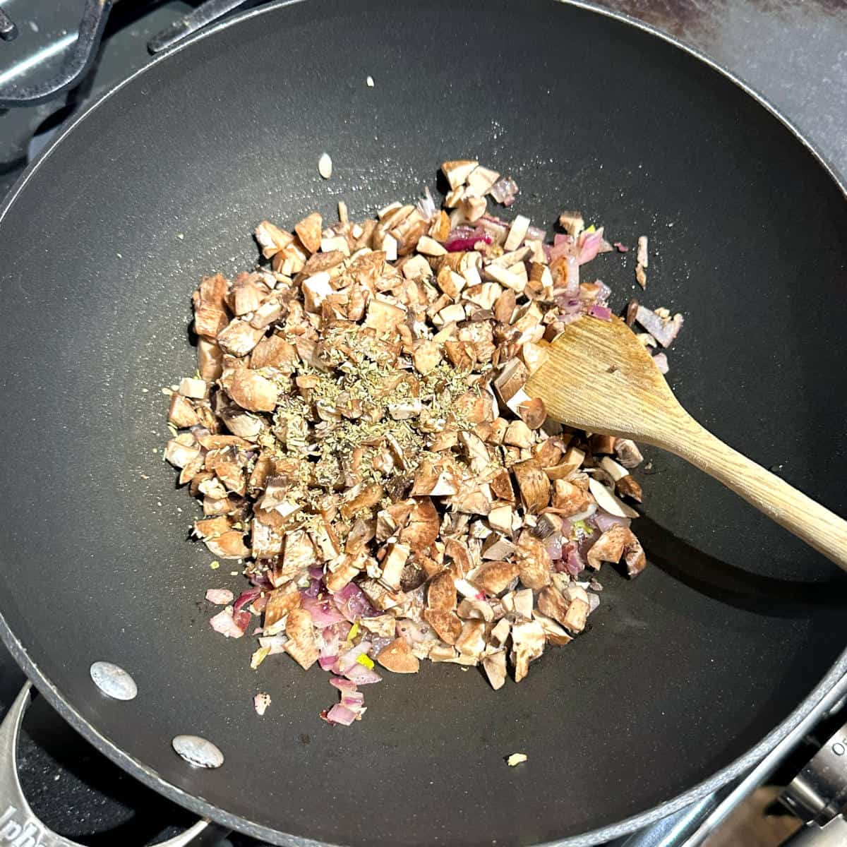 Mushroom stems, rosemary and oregano added to wok with garlic and onions.